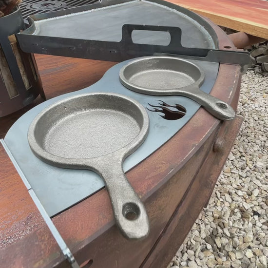 Odin PRO cart grill in rust: a quarter of the grate lifts out, firewood loads into the ember basket, and the crank raises the cooking surface